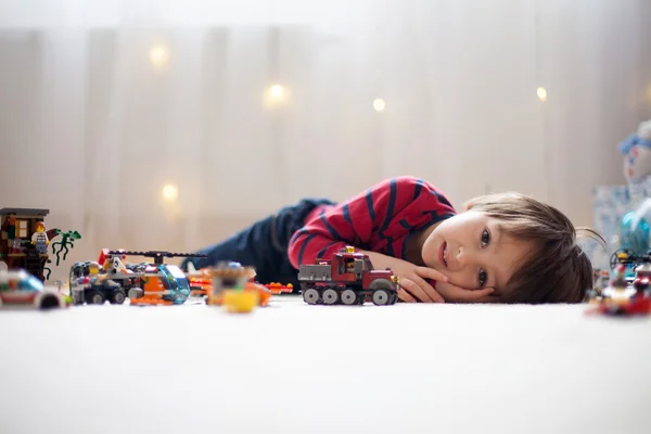 Küçük çocuk içeride bir sürü renkli plastik oyuncakla oynuyor. — Stok fotoğraf