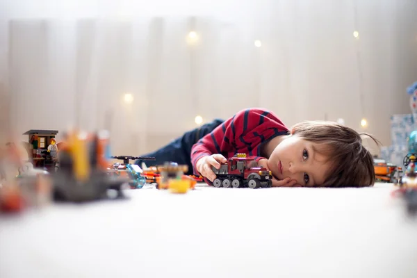 Bambino piccolo che gioca con un sacco di giocattoli di plastica colorati al coperto — Foto Stock