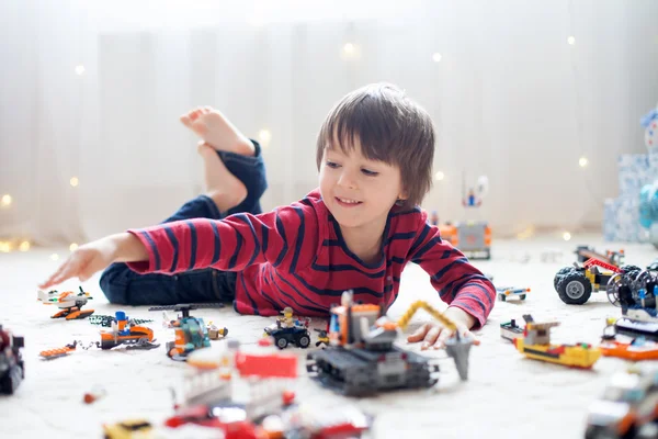 Pequeño niño jugando con un montón de juguetes de plástico de colores en interiores —  Fotos de Stock