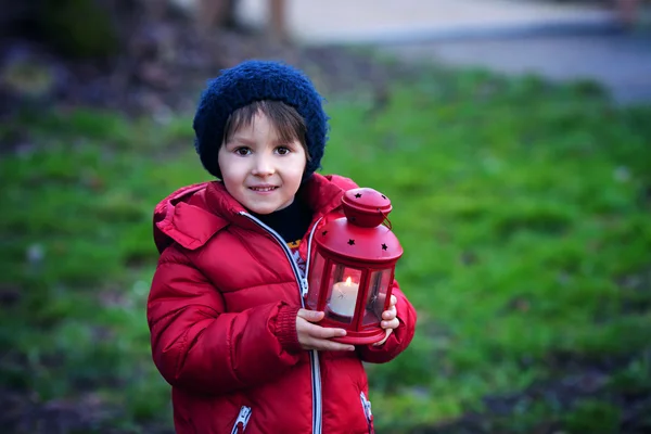 Enfant doux, tenant une lanterne rouge dans le parc pendant un hiver ensoleillé d — Photo