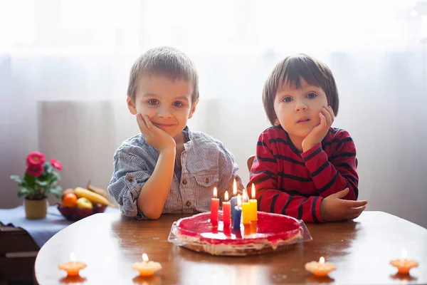 Adoráveis meninos bonitos, soprando velas em um bolo de aniversário — Fotografia de Stock