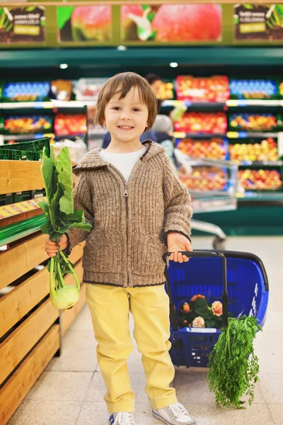 Bonito menino pequeno e orgulhoso ajudando com compras de supermercado, saudável — Fotografia de Stock