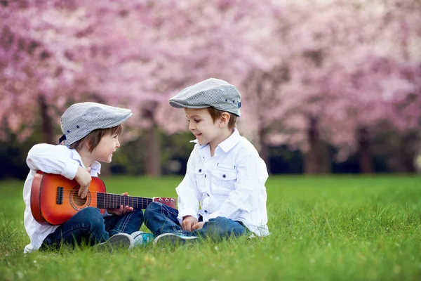 Dois meninos caucasianos adoráveis em um jardim de cerejeira florescente, pl — Fotografia de Stock