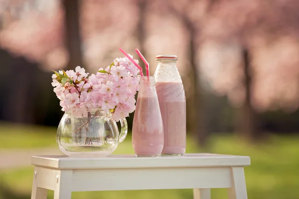 Strawberry smoothie freshly made in a jar, forest spring flowers — Stock Image Strawberry smoothie freshly made in a jar, forest spring flowers Royalty Free Stock Photos