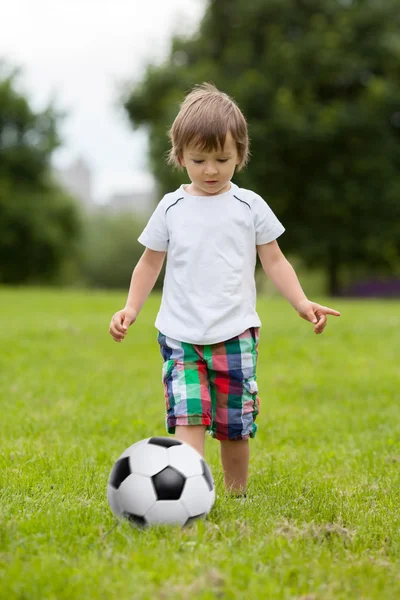 Menino bonito, jogando futebol no parque — Fotografia de Stock