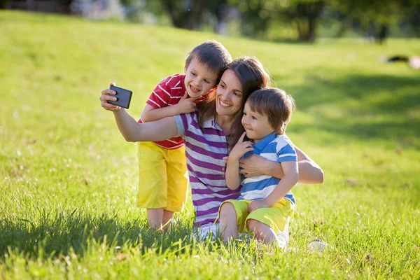 Gelukkig moeder met twee kinderen, nemen van foto's in het park, buiten — Stockfoto