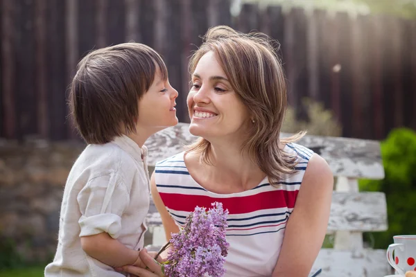 Beautiful mom, having coffee in a backyard, young cute child giv — Stock Photo, Image