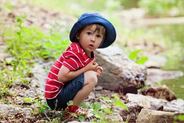 Retrato de un chico lindo con sombrero de verano en un borde de un río — Foto de Stock