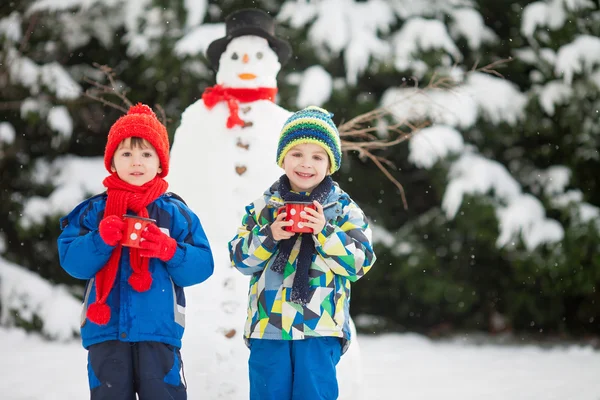 Szczęśliwy piękne dzieci, bracia, budowa snowman w ogrodzie — Zdjęcie stockowe