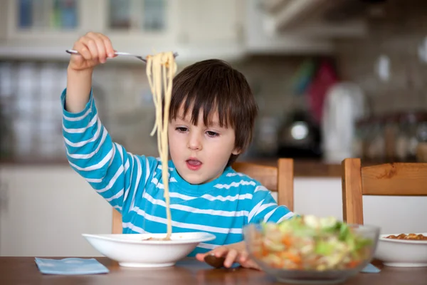 Söt liten pojke, äta spaghetti hemma för lunch — Stockfoto