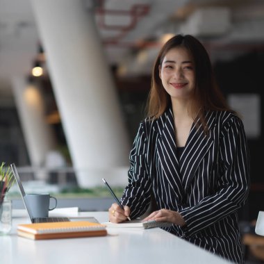 Modern ofis odasında kırtasiyeyle çalışan kadın portresi. 