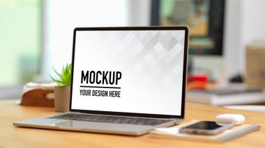 Dizüstü bilgisayar, akıllı telefon ve defterle ahşap masaya kesilmiş çalışma alanı görüntüsü.