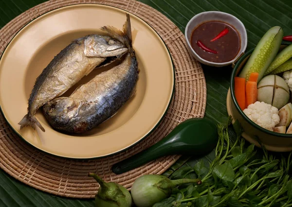 Muz yapraklarıyla süslenmiş Tayland geleneksel tabağında servis edilen karides ezmesi soslu ve sebze soslu kızarmış uskumru manzarası. 