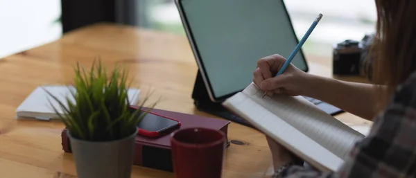 Vista Lateral Escritura Mano Femenina Cuaderno Blanco Mientras Utiliza Tableta — Foto de Stock