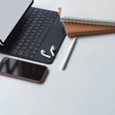 Tablet, akıllı telefon, defterler ve aksesuarlarla beyaz masa üzerinde çalışma alanının kırpılmış görüntüsü 
