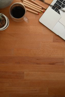 Fotokopi alanı, kahve fincanı, dizüstü bilgisayar ve kırtasiye malzemesi olan ahşap masanın üst görüntüsü