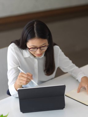 Modern ofis odasındaki tabletle projesinde çalışan iş kadınının en iyi görüntüsü 