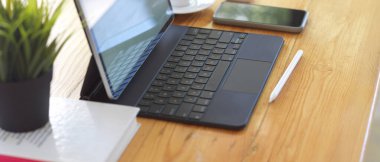 Ofiste dijital tablet, stilus, akıllı telefon ve malzeme içeren ahşap masa görüntüsü