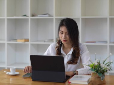 Tablet ve kitapla ödev yapan kız öğrencinin portresi ahşap masada. 