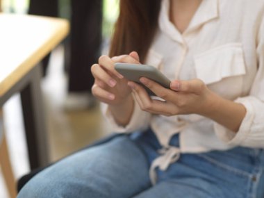 Kahve dükkanında otururken akıllı telefon kullanan kadınların ellerini kapat.