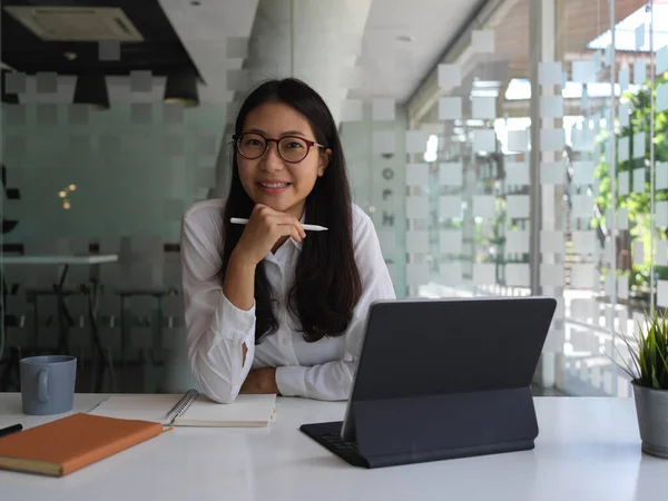 Ofiste ofis malzemeleriyle oturan gülümseyen kadın ofis çalışanının portresi.