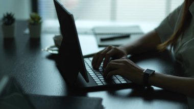 Ofis masasında çalışırken tablet klavyeye yazı yazan kadınların yan görünümü