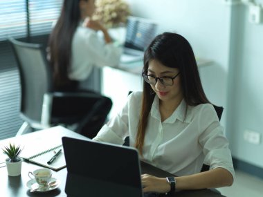 Ofis masasında ofis malzemeleriyle çalışan kadın ofis çalışanının kırpılmış fotoğrafı.