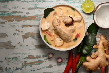 Tom Kha Gai 'nin üst görüntüsü, tavuklu hindistan cevizi sütü çorbası, ahşap masa üzerindeki Tayland yemeği ve fotokopi alanı.