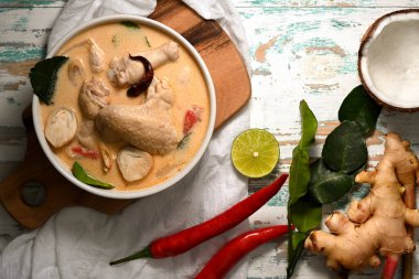 Tom Kha Gai 'nin üst görüntüsü, hindistan cevizi sütü çorbası ve tavuk, ahşap masada Tayland yemeği.