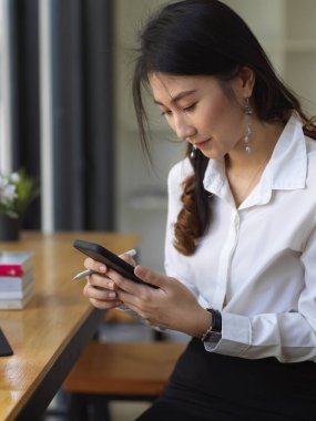 Bayan öğrencinin yan görünüşü ara verir ve ödev yaparken akıllı telefonla dinlenir.