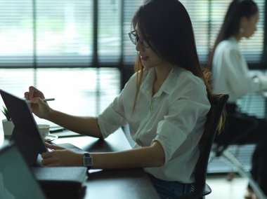 Ofis odasında tabletle çalışan kadın ofis çalışanının yan görüntüsü