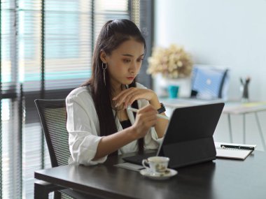 Ofis odasında dijital tabletle çalışan kadın ofis çalışanının yan görüntüsü