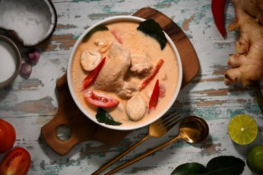 Tom Kha Gai 'nin üst görüntüsü, hindistan cevizi sütü çorbası ve tavuk, ahşap masada Tayland yemeği.