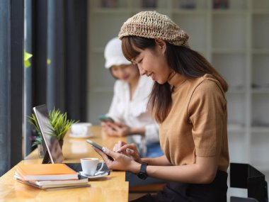 Rahat çalışma alanında akıllı telefon kullanan genç bir kadının görüntüsü. 
