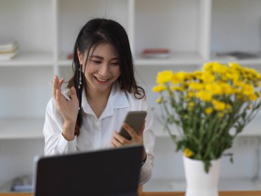 Kadın ofis çalışanının portresi, akıllı telefon kullanırken gülümseyen akıllı telefona ara verir.