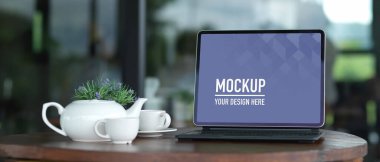 Çalışma alanı boş ekran tableti ile ahşap masa üzerinde çömlek çaydanlığı seti olan çalışma alanı