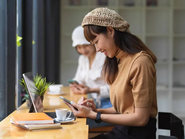 Rahat çalışma alanında akıllı telefon kullanan genç bir kadının görüntüsü. 