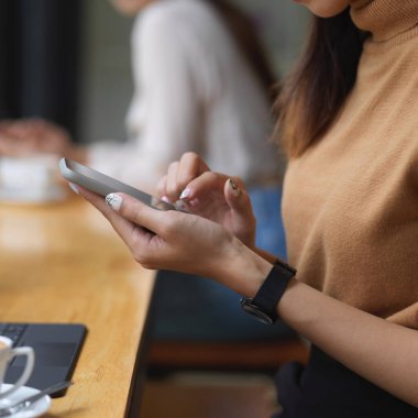 Rahat çalışma alanında akıllı telefonunu kullanan kız ellerinin yan görüntüsü