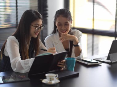 İki profesyonel iş kadını ofis odasında projeyi tartışıyor. 