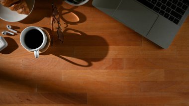 Üst kattaki ahşap masa, fotokopi odası, dizüstü bilgisayar, kahve fincanı ve malzeme.