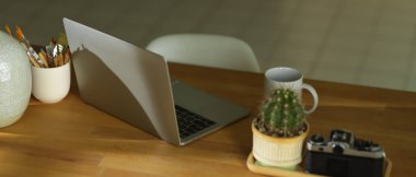 Bilgisayarlı, kameralı, malzemeli ve ahşap masadaki dekorasyonlu çalışma alanı. 