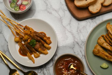 Fıstık soslu ızgara domuz pastırması (Moo Satay) ve mermer yemek masasında meze. 