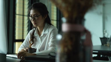 Ofiste bilgisayarla çalışmaya konsantre olan bir kadının portresi.