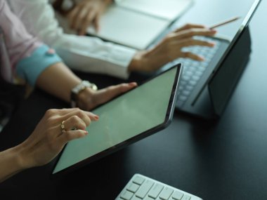 Dijital cihazlarla projelerinde birlikte çalışan iki kadın işçinin yakın görüntüsü