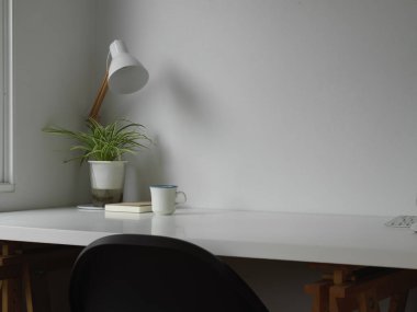 Çalışabilir masa lambası, saksı ve sandalyeli beyaz konsept ofis odası. 