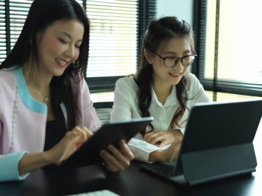 Dizüstü bilgisayar ve tabletle projelerinde birlikte çalışan iki kadın işçinin portresi