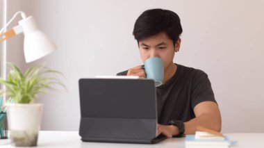 Ofiste dijital tabletle çalışırken kahve içen erkek portresi