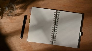 Tahta masadaki boş defter ve kalemin üst görünümü 