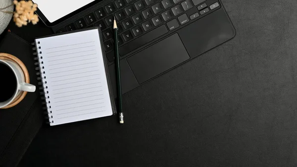 Top view of workspace with stationery, laptop, coffee cup and copy space on black table