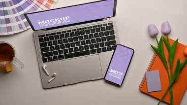 Masada akıllı telefon, dizüstü bilgisayar, malzeme ve çiçek bulunan en iyi çalışma tablosu